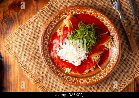 Entomatadas. Also known as Enjitomatadas, a typical dish of Mexican cuisine prepared with corn tortilla, tomato sauce and stuffed with shredded chicke Stock Photo