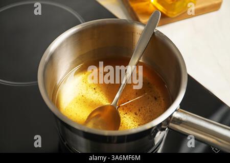 Used cooking oil and spoon in saute pan on stove, closeup Stock Photo