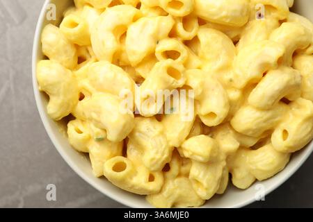 Delicious pasta with cheese sauce in bowl on grey table, top view Stock Photo