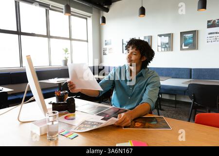 Reviewing design prints, creative professional working at modern office desk Stock Photo
