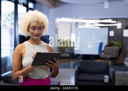 African American woman using digital tablet in modern office, focused on work, copy space Stock Photo