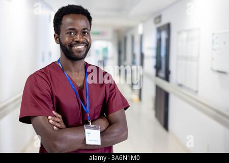 Smiling healthcare professional in scrubs standing confidently in hospital corridor Stock Photo