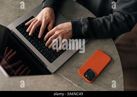 Close-up high-angle view of unrecognizable freelancer remote working from home office, developing software solutions, sitting at table by window in Stock Photo
