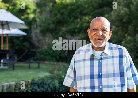 Senior man in plaid shirt enjoying sunny day outdoors in garden, copy space Stock Photo