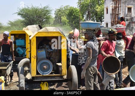 Construction workers carrying gravel and working at a building site ...