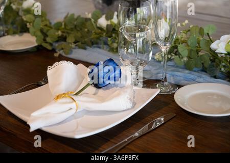 Decorations for the wedding receptions party have a single blue rose on each table setting for the guests. Stock Photo