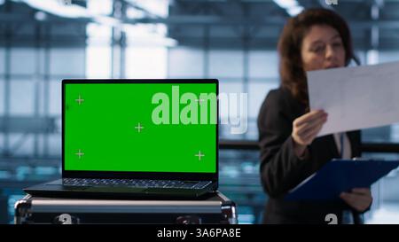 Green screen laptop used by data center admins in blurry background reviewing equipment diagnostics. Chroma key notebook used by coworkers adjusting server room configurations, camera A Stock Photo