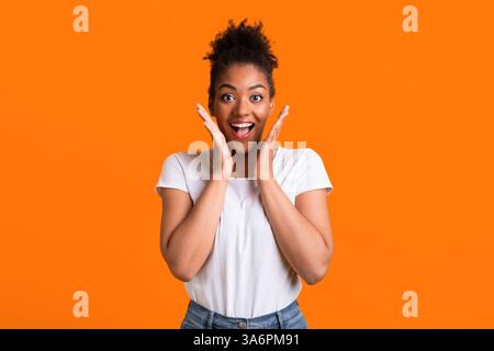 Happy afro woman screaming and holding cheeks Stock Photo