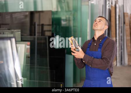 Worker using remote control to operate machinery in glass workshop Stock Photo