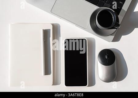 Tech Professional Setup. Overhead Shot of Laptop, Phone, Mouse and Notebook on Sleek Desk. Stock Photo