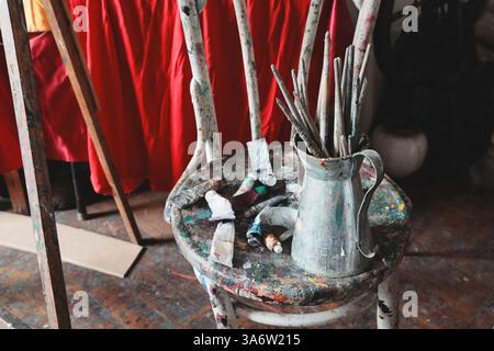 An Artistic Setup Featuring Brushes and Paints Situated on a Wooden Chair for Creative Projects Stock Photo