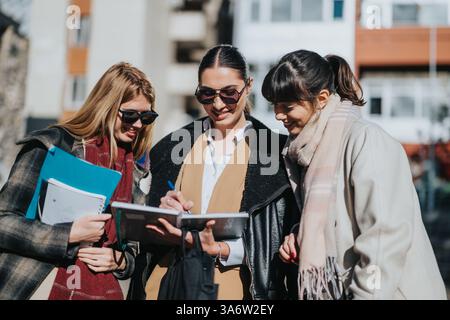 Three young women collaborating outdoors on a sunny urban day Stock Photo