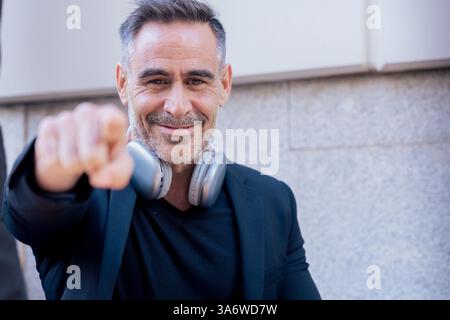 Confident caucasian businessman with headphones smiling and pointing at the camera,copy space Stock Photo