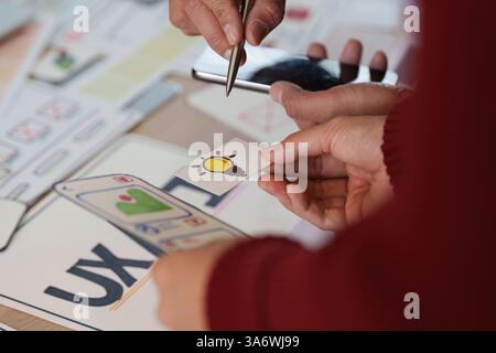 Exploring Ideas in UX UI Design. Hands holding a creative lightbulb symbol during a collaborative design discussion. Stock Photo