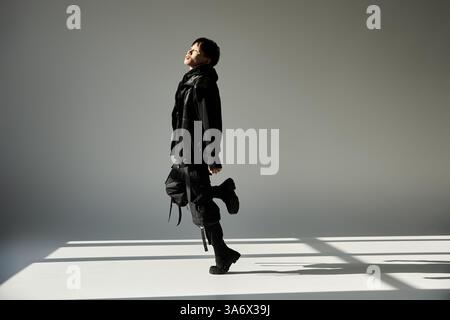 A young, handsome Asian man poses confidently in stylish black against a minimal backdrop. Stock Photo