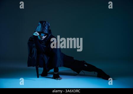 Handsome man dressed in stylish black attire strikes an artistic pose with a confident expression. Stock Photo