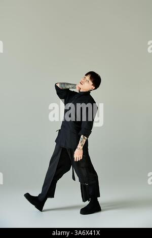 A tattooed young man strikes a stylish pose in a simple setting. Stock Photo