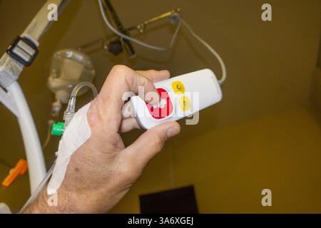 man presses the nurse call button, drip with access via the back of the hand, Germany Stock Photo