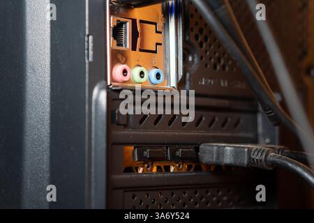 Close-up of a computer's back panel showing various ports including Ethernet, audio jacks, and SUB connections, with cables plugged in. Stock Photo