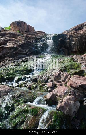 Small waterfall, falling of water behind the rock Stock Photo - Alamy