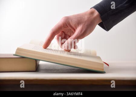 Concept of a person reading a book with a red registration tape pointing at text with your finger isolated on a purple background. Top view. Stock Photo