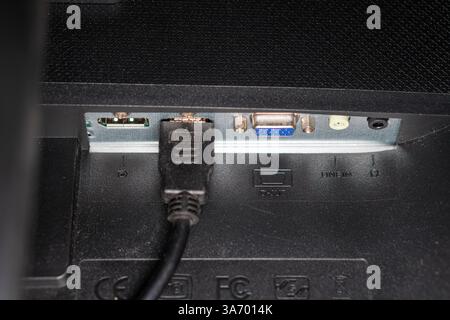 Close-up view of the back panel of a monitor showing various ports including HUMID, VGA, and audio input. A power cable is connected, highlighting the Stock Photo