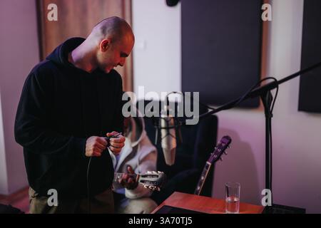 The image captures a musician and a producer working together in a modern recording studio. Stock Photo