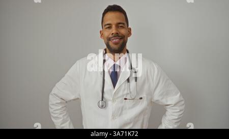 Hispanic male doctor smiling confidently with stethoscope over white background depicting healthcare and professionalism. Stock Photo