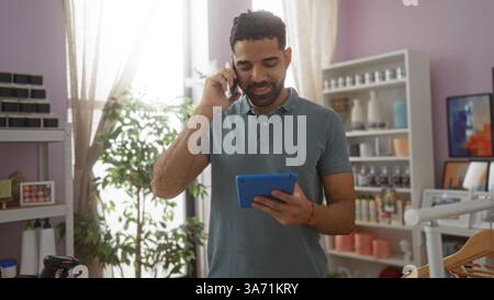 Young man talking on phone while using tablet in a home decor shop filled with various decorations and bright plants. Stock Photo