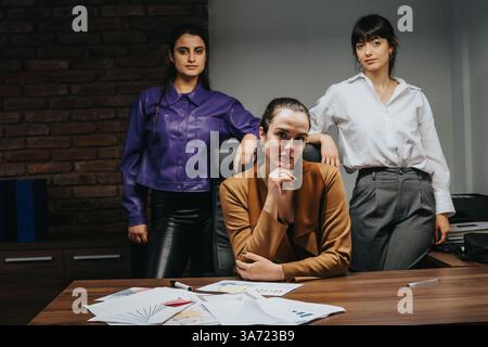 Confident team of three professionals collaborating in a modern office setting Stock Photo