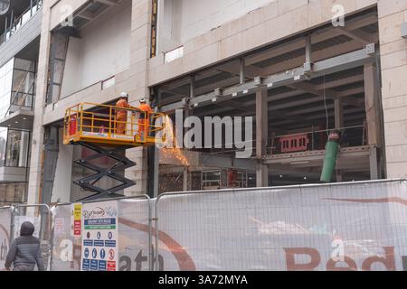 Welders at work on a commercial construction project in Buchanan Street, Glasgow city centre, Scotland.  Sparks visible from the welding equipment. Stock Photo