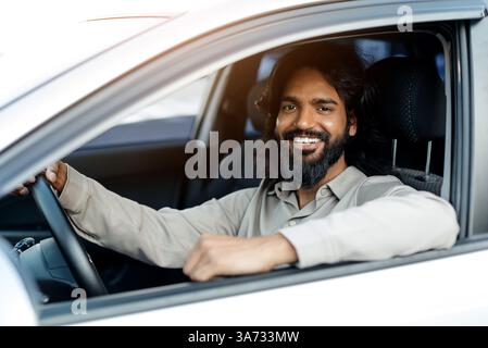 Smiling Indian man sitting in car, arm resting on the window Stock Photo