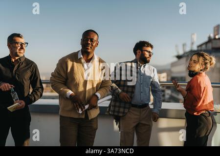 A diverse group of business people relax and enjoy music on a high-rise balcony. Stock Photo