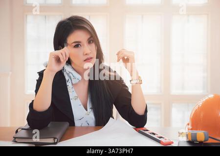 Female architect working on blueprint architects project in office. Stock Photo