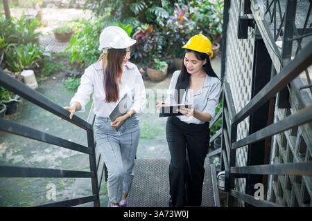 Two young female architects chatting as they walk up the stairs. Stock Photo
