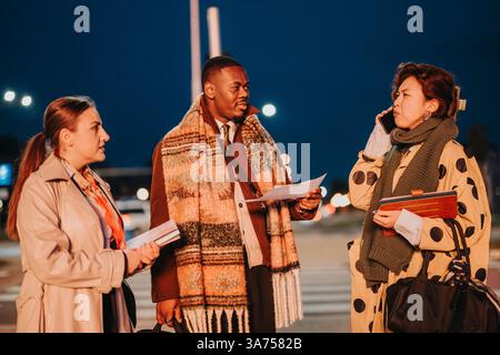 Multiracial business people collaborating outdoors during an evening meeting Stock Photo