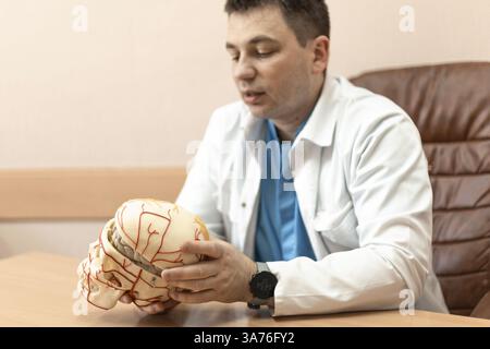 male doctor holding a model of a human skull with brain Stock Photo