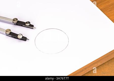 Design Accuracy: Close-up of a compass meticulously drawing a perfect circle on a clean sheet of paper placed on a brown wooden table, conveying the e Stock Photo