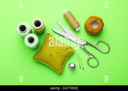 Different sewing supplies on green background, flat lay Stock Photo
