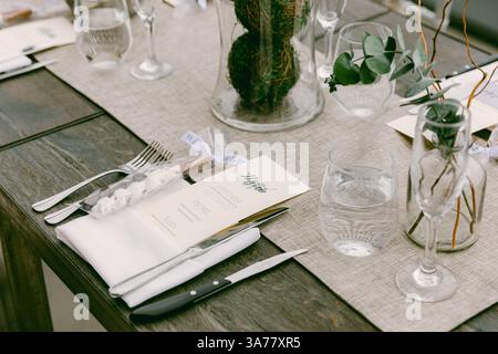 A beautifully arranged table showcases stylish utensils, soft linens, and natural elements for a festive gathering. Stock Photo