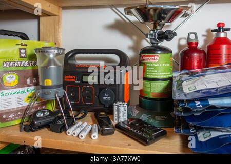 Emergency kit at home including portable power station, flashlight, spare batteries, pocket radio, camping stove, freeze-dried meals, fuel and water Stock Photo