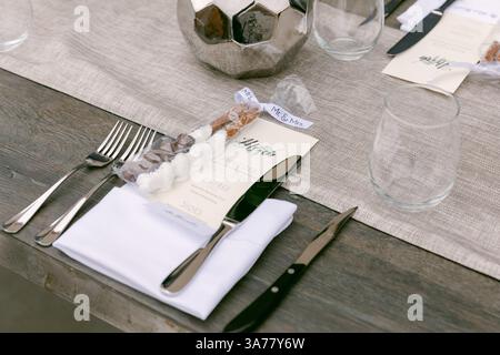 An inviting dining arrangement with elegant silverware, glasses, and personalized menus set for a festive gathering. Stock Photo