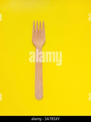 Organic bamboo disposable fork on yellow background. Environmentally friendly wooden fork. Ecology, zero waste concept with copy space. Stock Photo