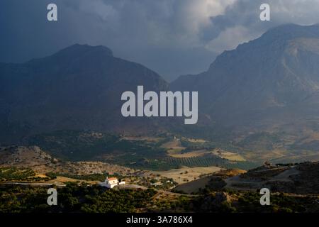A chapel against a backdrop of mountains under a stormy sky, southern Crete Stock Photo