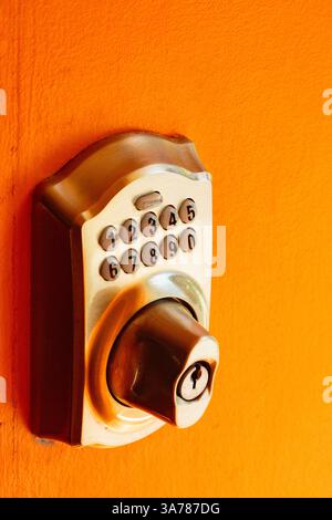 Electronic Door lock and key pad on an orange background, close up. Stock Photo