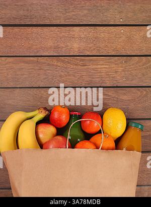 Paper eco bag with healthy vegan products for weight loss. Lemons, oranges, tomatoes, apples, bananas and natural juice in a craft bag, food delivery Stock Photo