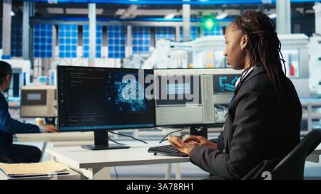 Photovoltaics factory programmer using AI technology to monitor system performance. Solar panels manufacturing plant developer using artificial intelligence to track energy production, camera A Stock Photo