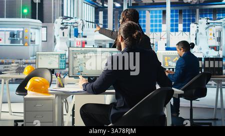 Eco friendly photovoltaics factory manager working with solar engineering team, improving systems reliability. Sustainable energy solar panel manufacturing plant expert providing feedback to workers Stock Photo