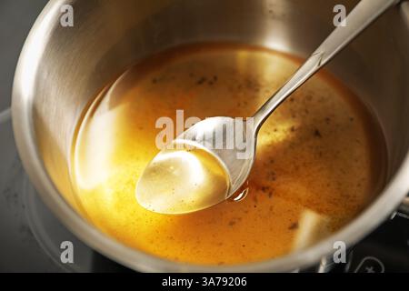 Used cooking oil and spoon in saute pan on stove, closeup Stock Photo