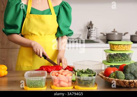 Woman cutting bell pepper for freezing on wooden table in kitchen Stock Photo